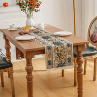 Chemin de Table Beige Motif Éléphant Original sur une table avec des assiettes, une tasse, des fleurs et une planche en bois