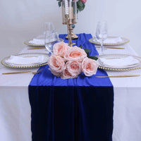 Chemin de Table Bleu Luxueux en Velours sur une table avec des assiettes, des couverts, des verres, des bougies et des fleurs