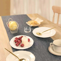 Chemin de Table en Jute Tendance et Durable sur une table avec des assiettes, des cuillères, des aliments et un verre