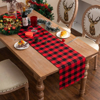 Chemin de Table Rouge Décoratif à Carreaux sur une table avec des assiettes, des couverts, un verre, une bouteille et de la décoration de Noël