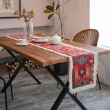 Chemin de Table Rouge avec Frange et Motifs sur une table en bois avec une tasse, des plantes, des assiettes et des couverts