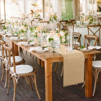 Chemin de Table Toile de Jute Discret et Robuste sur une grande table en bois avec des assiettes, des couverts, des verres, des serviettes et des fleurs