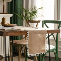 Chemin de Table en Toile de Jute Élégant et Classe sur une table en bois avec des assiette, un livre et une bougie