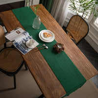 Chemin de Table Vert en Macramé Fait Main sur une table en bois avec des assiettes, des couverts, une tasse, un magazine, une plante verte et une bougie