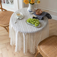 Nappe blanche ronde en dentelle fine sur une table avec des fleurs et raisins dessus