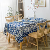 Nappe Bleu Rectangulaire à Motif Floral Élégant sur une table avec des assiettes, des couverts, des fleurs et un réveil