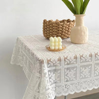 Nappe Carrée en Dentelle avec Motif Floral, de couleur beige, sur une table carrée en bois.