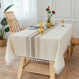 Nappe Coton Rectangulaire et Blanche avec Pompons, dans une salle à manger, avec chaises en bois.