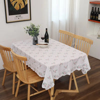 Nappe coton rectangulaire avec motif floral, de couleur blanche, dans une salle à manger avec quatre chaises en bois.