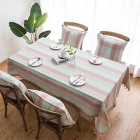 Nappe Coton Rose à Rayures avec Pompons, dans une salle à manger, avec chaises avec coussins assortis à la nappe.