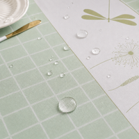 Gros plan sur une nappe imperméable verte avec effet déperlant et motif graphique moderne sur table de salle à manger lumineuse